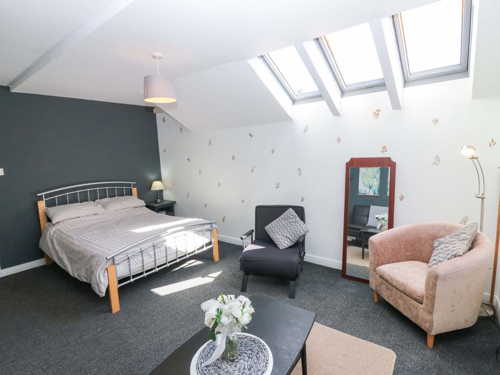A bedroom with a bed and seating area at Apartment 2 in Dyce