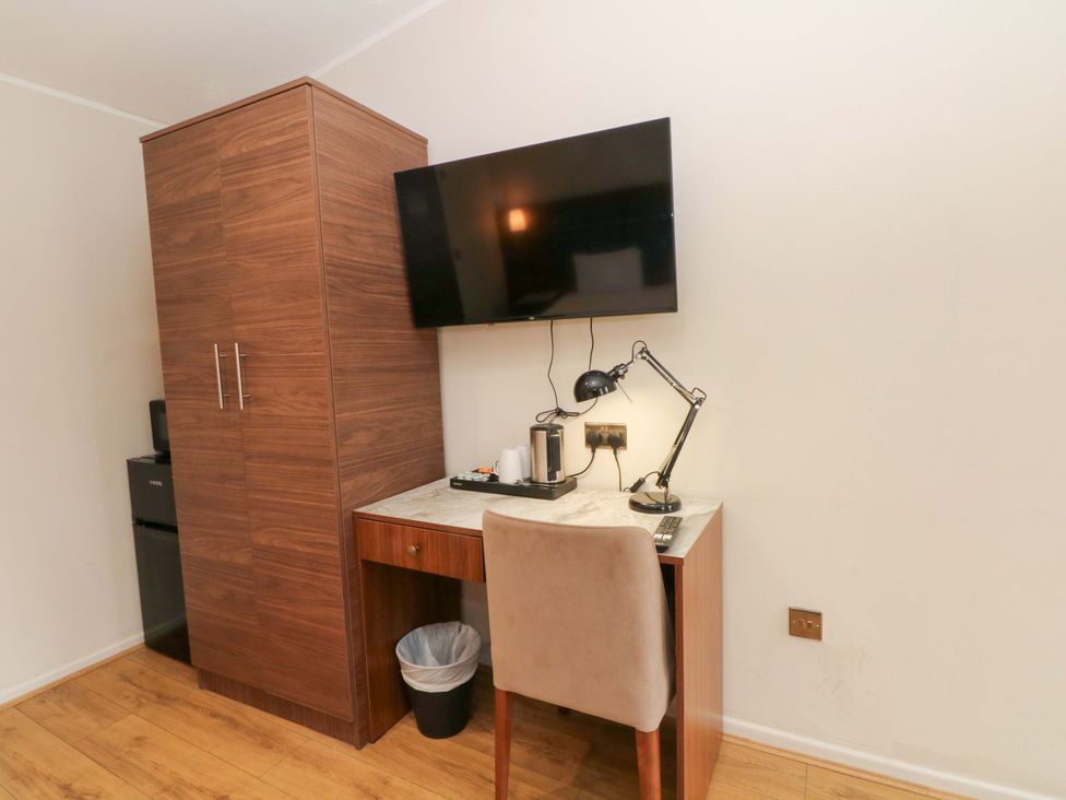 An office with a desk, chair, TV, and wardrobe at 1 bed no. 2 Chorley