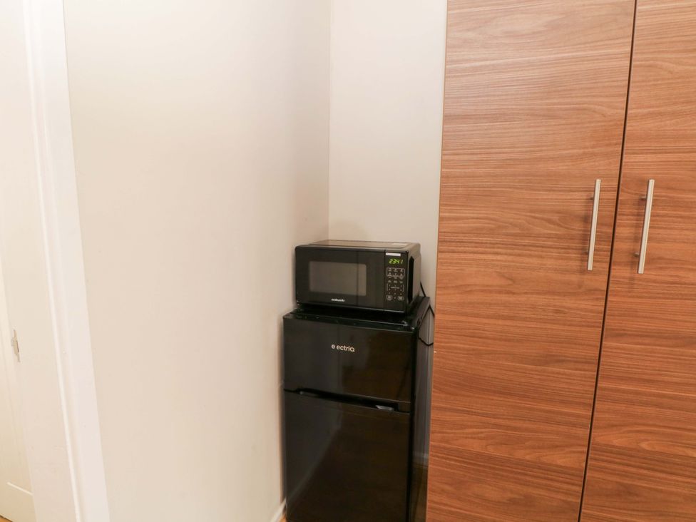A microwave on top of a refrigerator in a kitchen at 1 bed no. 3 Chorley