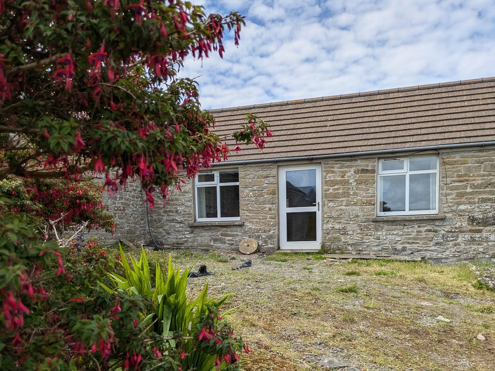 A stone house with windows and a door at Rousey Cottage Rousay, Orkney Islands