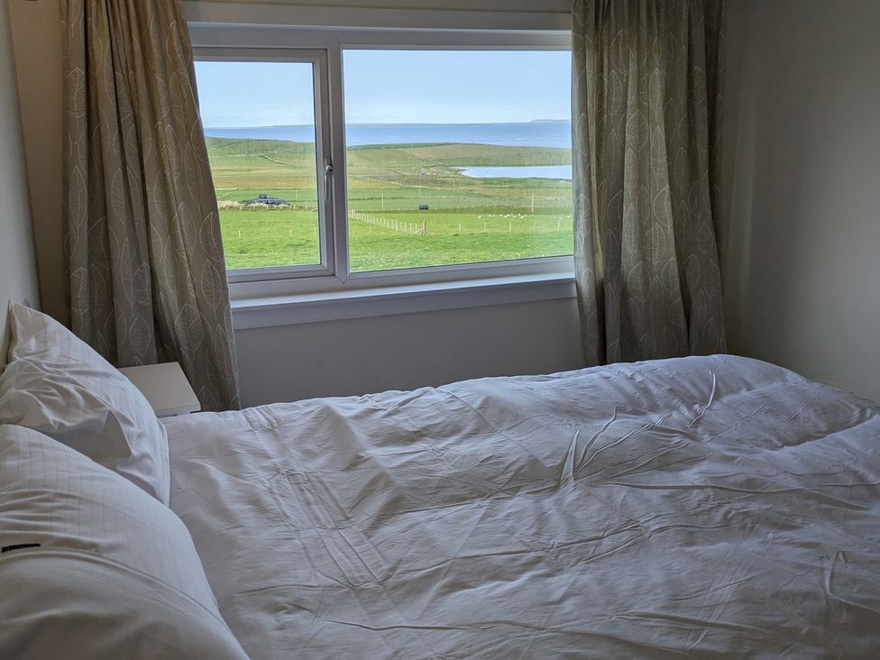 A bedroom with a bed and window at Rousey Cottage in Rousay, Orkney Islands