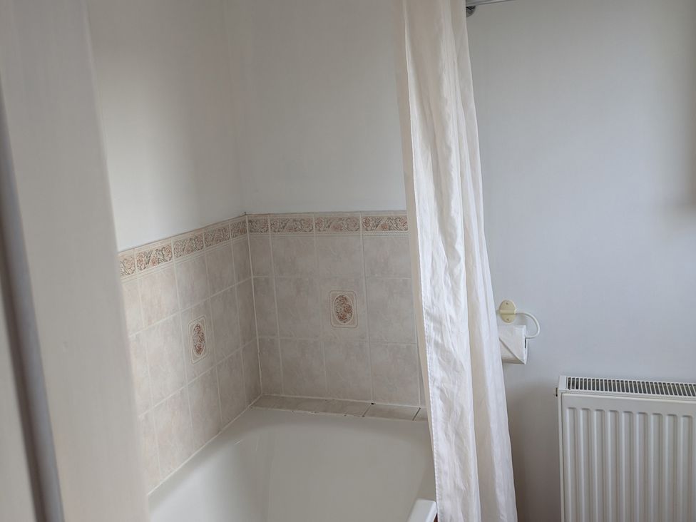 A bathroom with a bathtub and a shower curtain at Rousey Cottage Rousay, Orkney Islands
