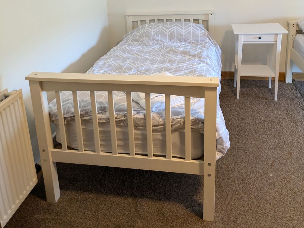 A bedroom with a bed and nightstand at Rousey Cottage in Rousay, Orkney Islands