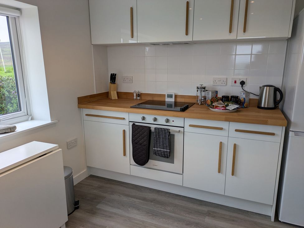 A kitchen with white cabinets and wooden countertop at Lower Hammerfield Rousay, Orkney Islands