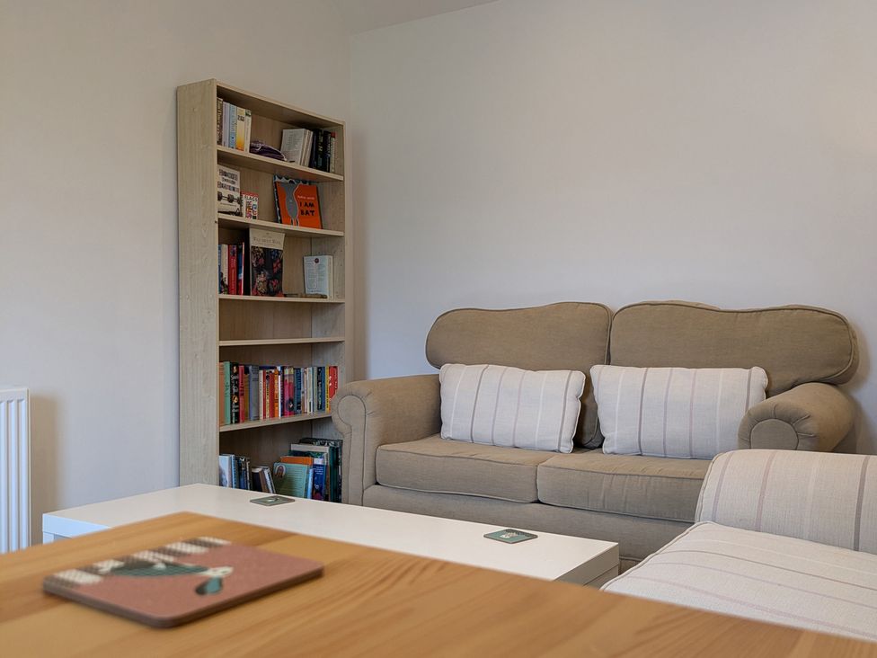 A living room with a sofa and bookshelf at Lower Hammerfield, Rousay, Orkney Islands