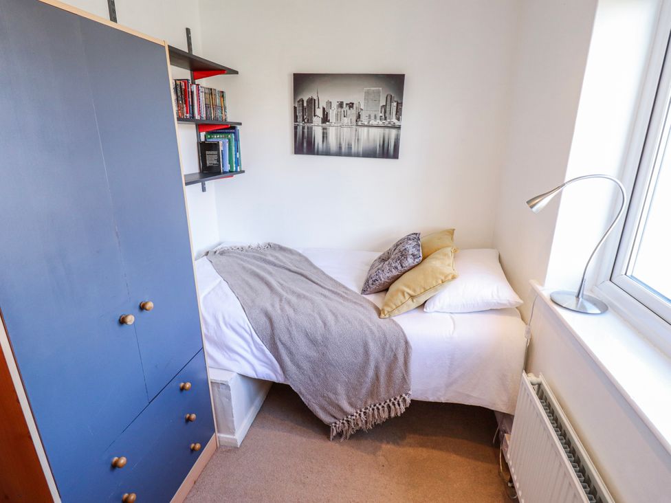 A bedroom with a bed, shelf with books, and a wardrobe at 55 Broadway in Lincoln