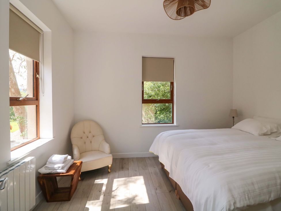 A bedroom with a bed, armchair and windows at The Mews @ Suskar, Laragh, County Wicklow