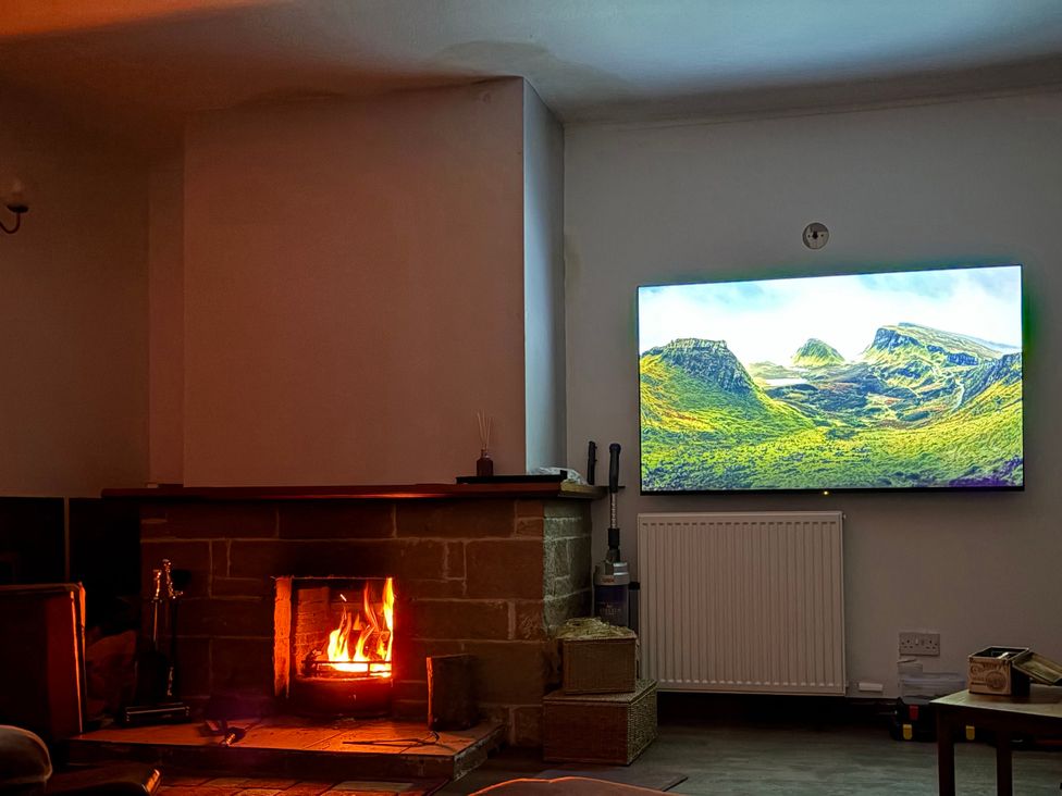 A living room with a fireplace and a television at Woodview in Isle of Barra