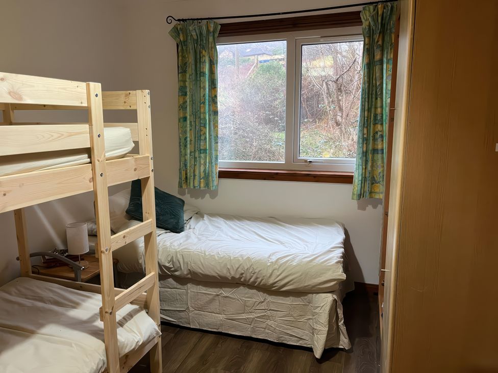 A bedroom with a bunk bed and a single bed at Woodview, Isle of Barra