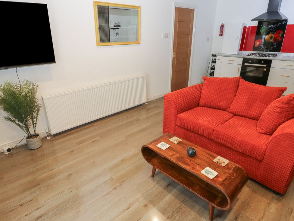 A living room with a red couch and a wooden table at No.1 Spa Mill Lodge in Huddersfield