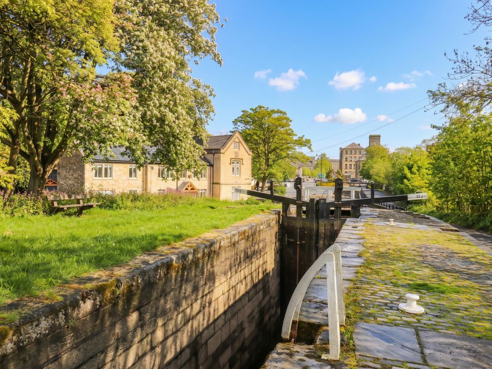 A lock on a waterway with trees and buildings at No.1 Spa Mill Lodge Slaithwaite