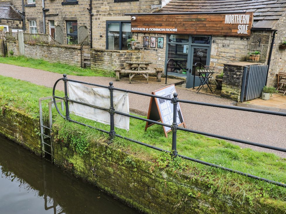 A building with outdoor seating and a canal at No.1 Spa Mill Lodge, Slaithwaite