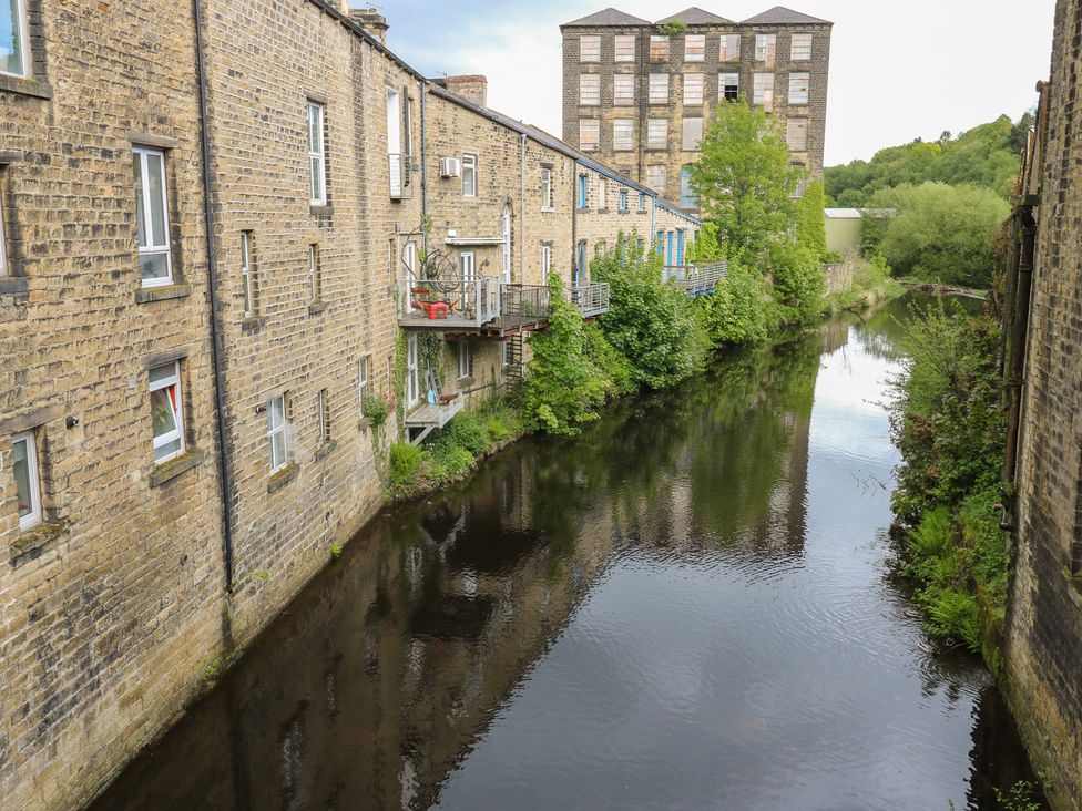 A scene featuring buildings alongside a river with trees at No.1 Spa Mill Lodge Slaithwaite