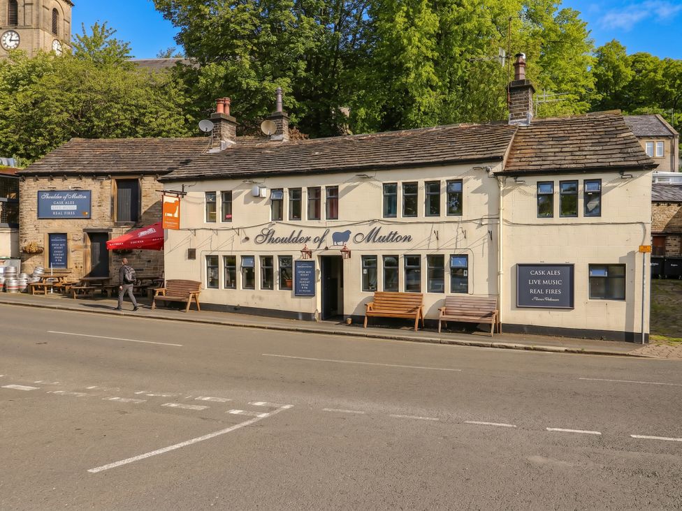 An exterior view of a pub with benches and signage at No.1 Spa Mill Lodge Slaithwaite