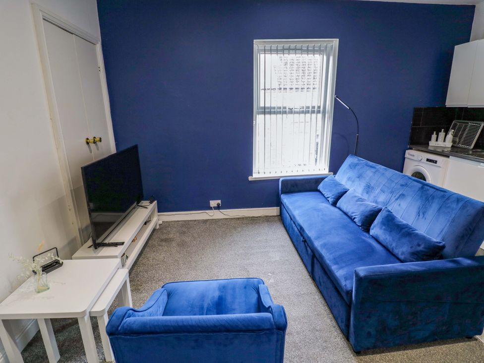 A living room with a blue sofa and TV at 1C Highfield Road - 2 bed Rowley Regis