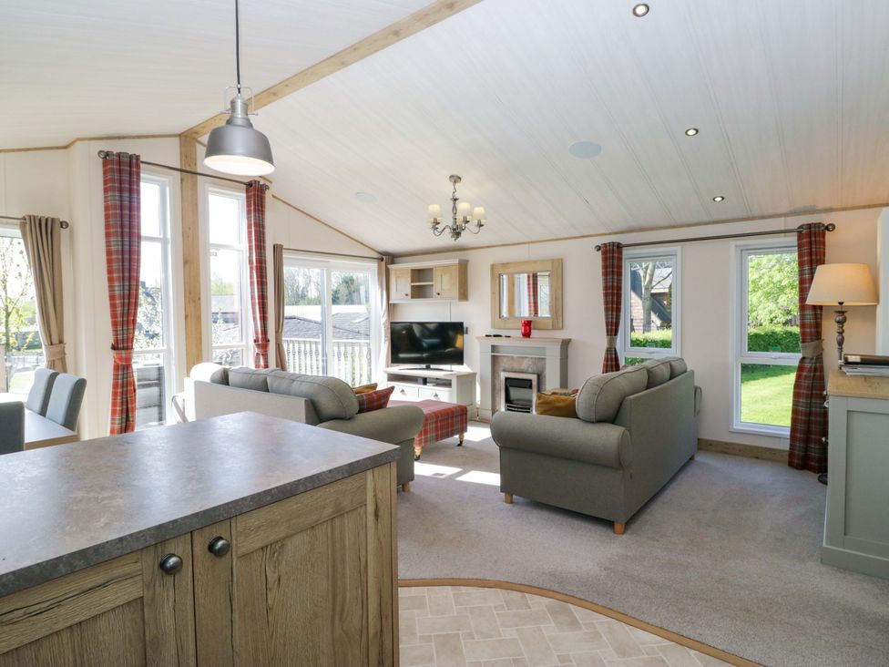 A living room with a sofa, television, and fireplace at Borwick Heights 17 in Carnforth