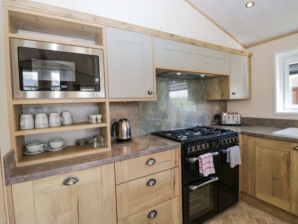 A kitchen with a microwave, kettle, and cooking range at Borwick Heights 17 in Carnforth