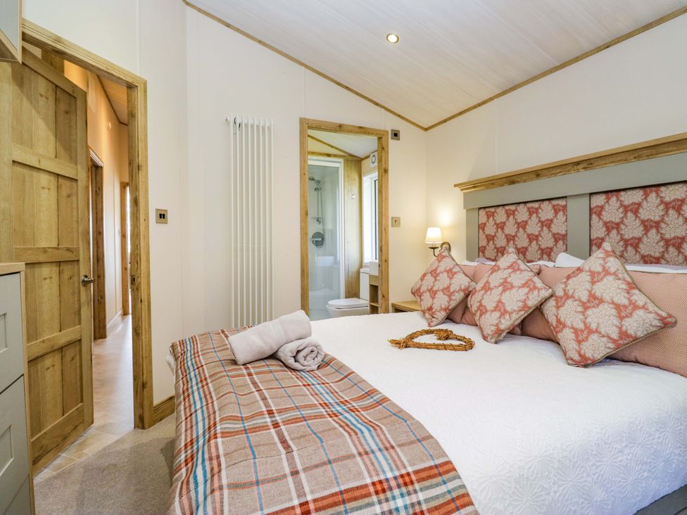 A bedroom with a bed and bathroom access at Borwick Heights 17 Carnforth