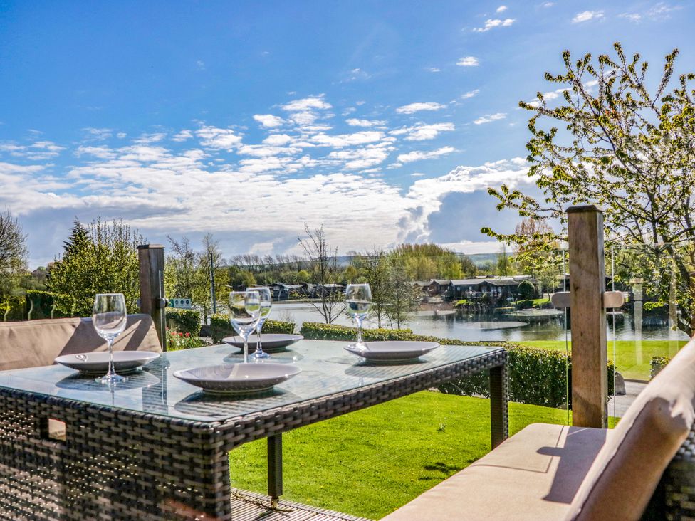 A table set with glasses and plates overlooking a lake at Borwick Heights 17 Carnforth