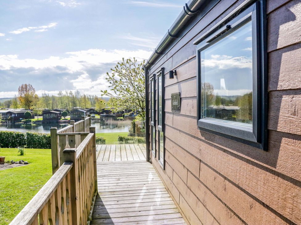 A wooden cabin exterior with deck and view of water at Borwick Heights 17 Carnforth