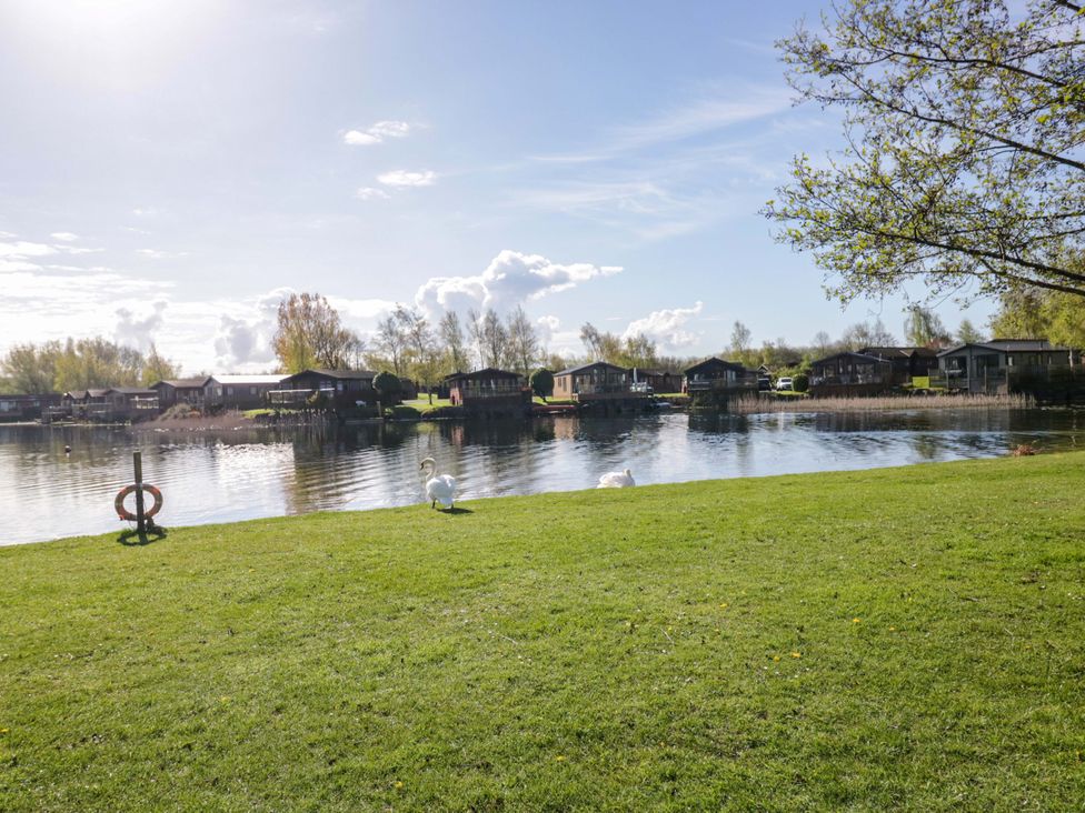 A lake with swans and cabins at Borwick Heights 17 in Carnforth