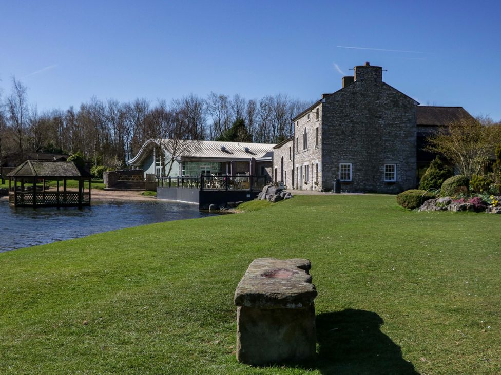 A house beside a lake with a bench in the garden at Borwick Heights 17 Carnforth