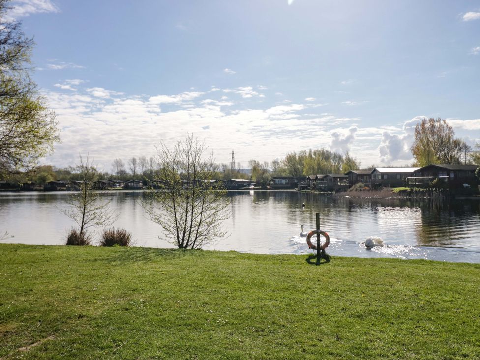A scenic view of a lake with swans and cabins at Borwick Heights 17 in Carnforth