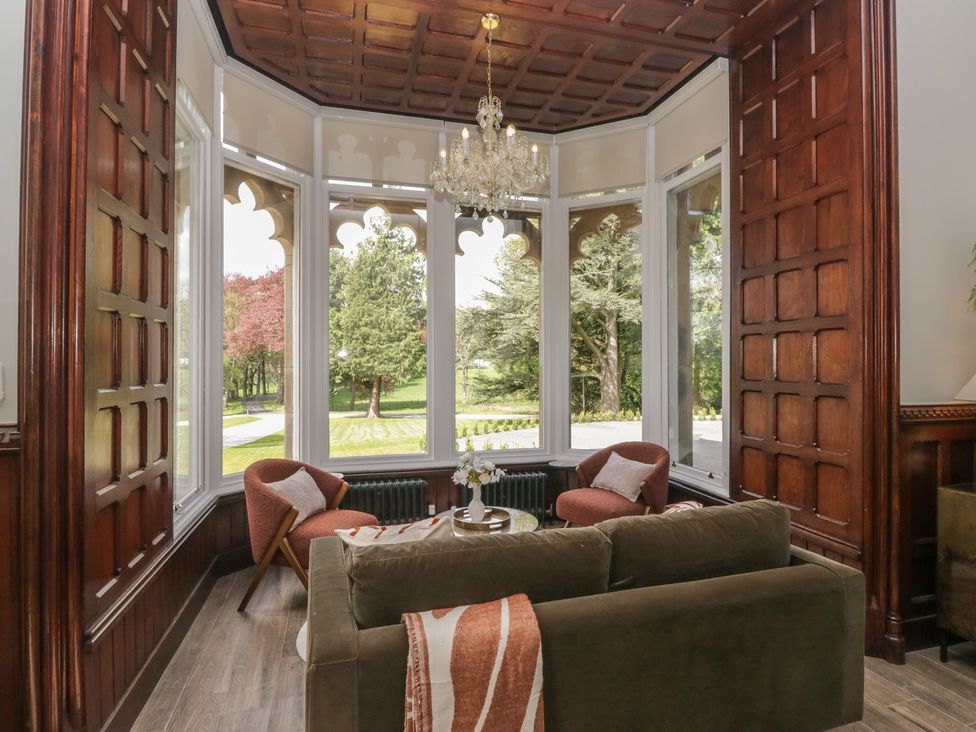 A living room with a sofa and armchairs and large windows at Brettargh Holt Mansion near Levens