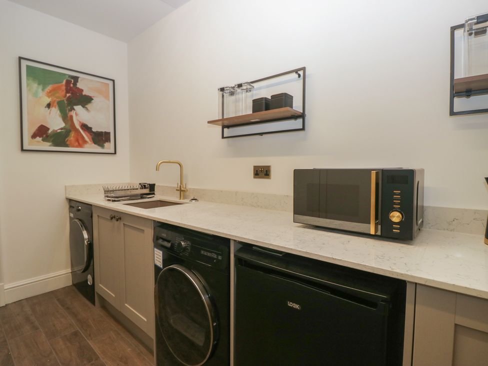 A laundry room with a washing machine and microwave at Brettargh Holt Mansion near Levens