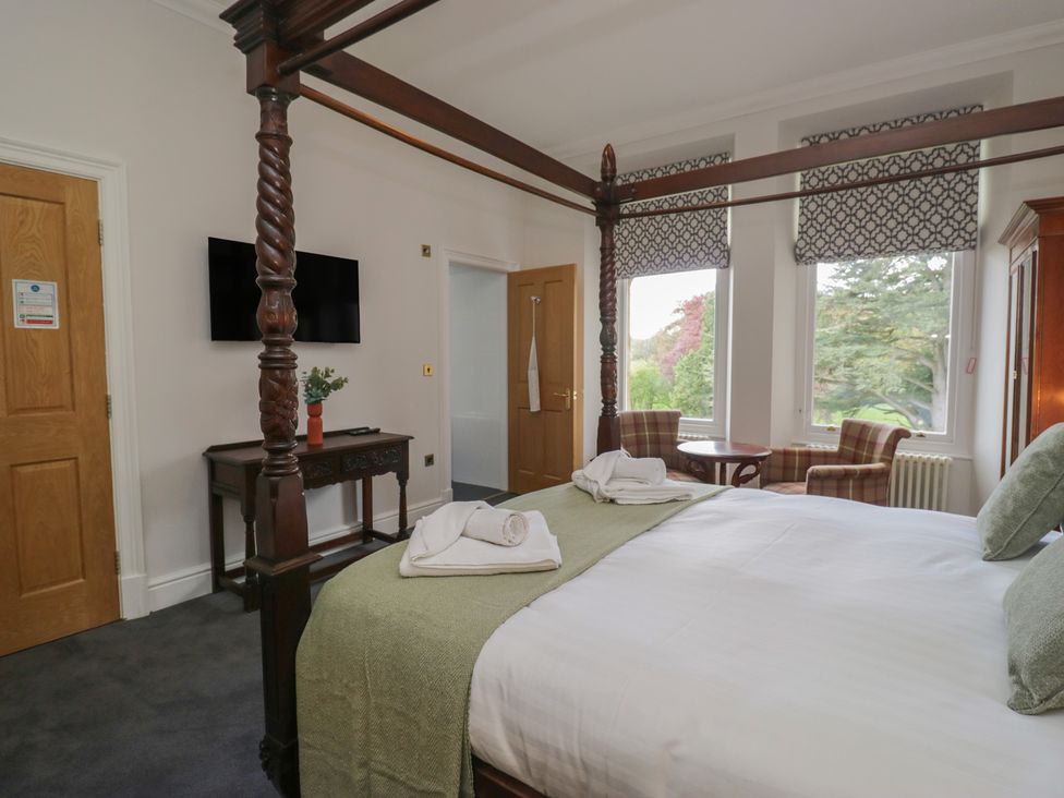 A bedroom with a four-poster bed and seating area at Brettargh Holt Mansion near Levens