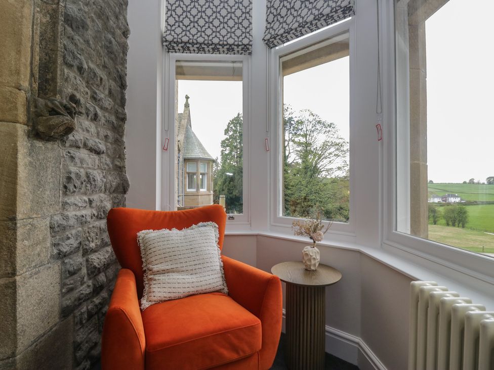 A snug featuring an orange chair and side table at Brettargh Holt Mansion near Levens