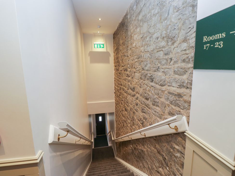 A staircase with a stone wall and exit sign at Brettargh Holt Mansion near Levens