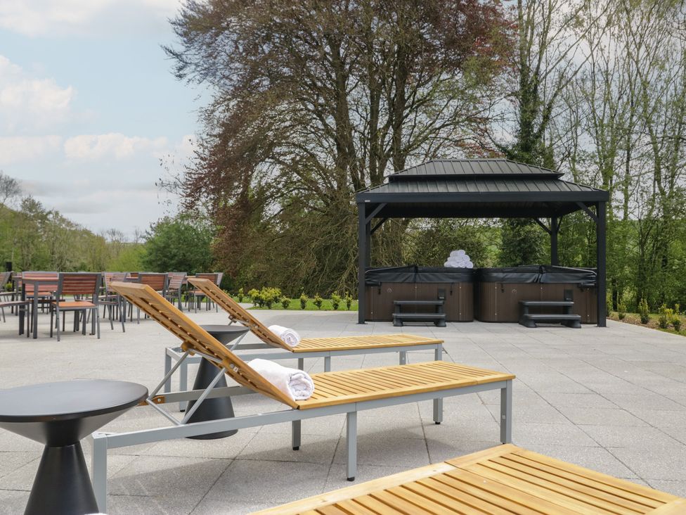 An outdoor patio with sun loungers and a hot tub at Brettargh Holt Mansion near Levens