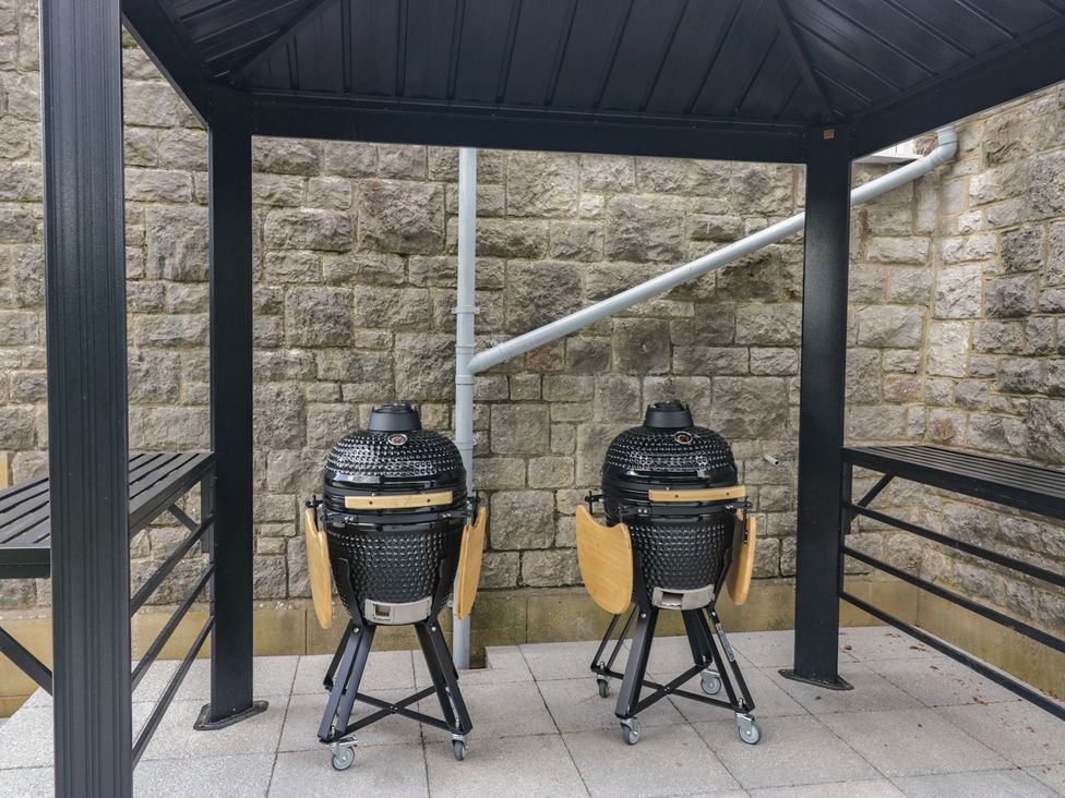 Two grills under a shelter with a stone wall at Brettargh Holt Mansion near Levens