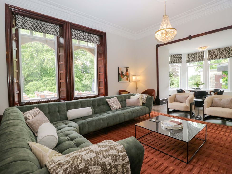 A living room with a green sofa and a glass table at Brettargh Holt Mansion Sleeping 48 near Sizergh, Cumbria