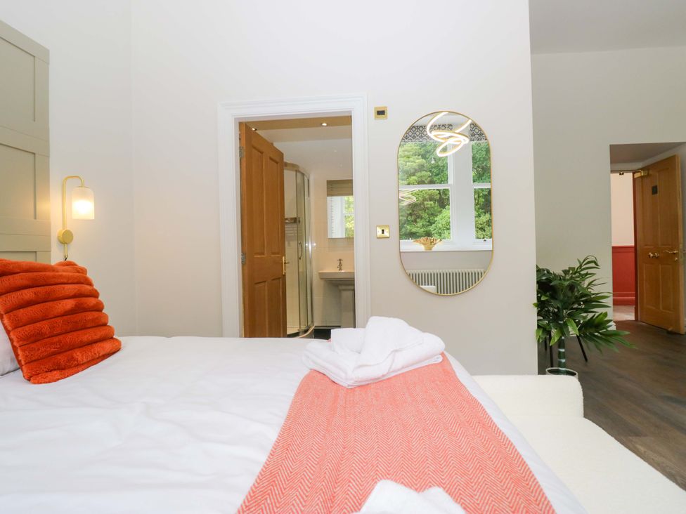 A bedroom with a bed and bathroom access at Brettargh Holt Mansion Sleeping 48 near Sizergh, Cumbria