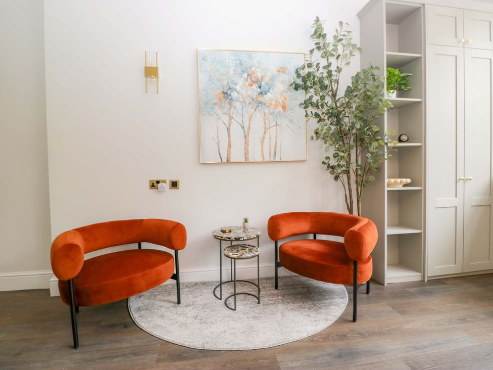 A living room with orange chairs and a small table at Brettargh Holt Mansion Sleeping 48 near Sizergh, Cumbria