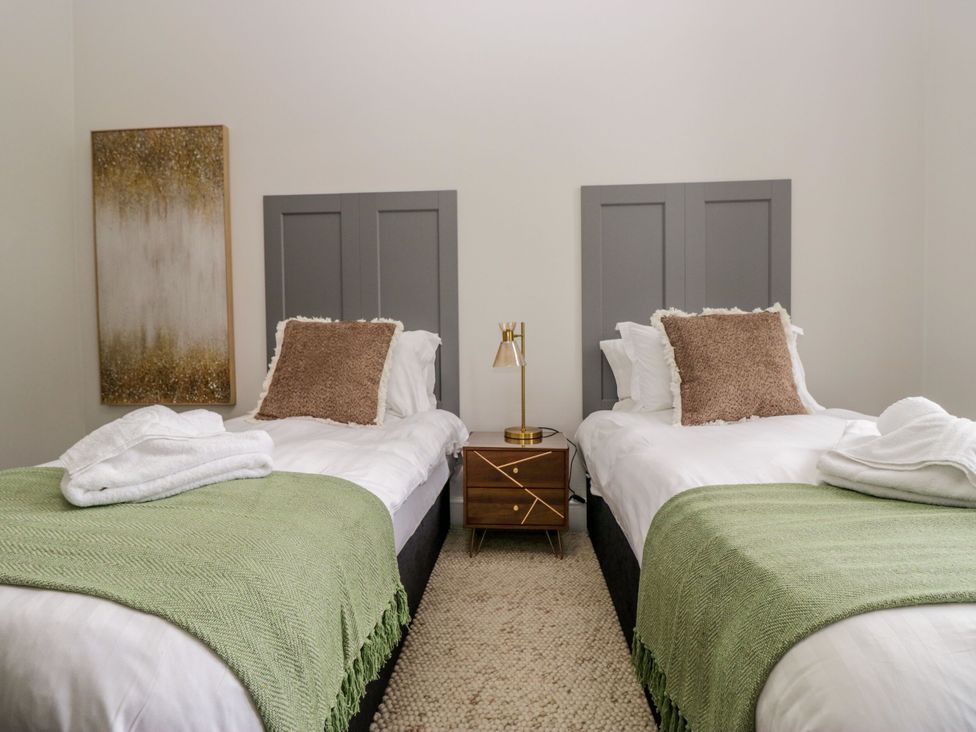 A bedroom with twin beds and a bedside table at Brettargh Holt Mansion 32 near Levens