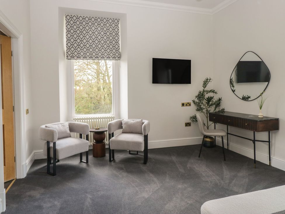 A living room featuring two chairs, a television, table and plant at Brettargh Holt Mansion 32 near Levens