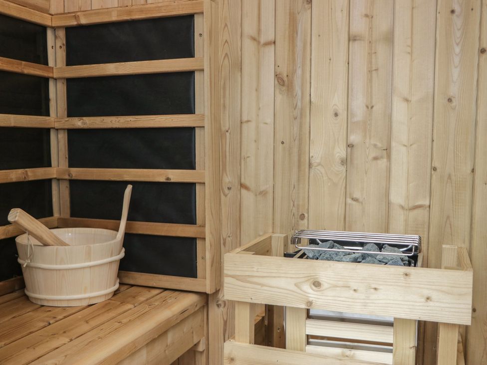 A sauna with a wooden bench, bucket, and heater at Brettargh Holt Mansion 32 near Levens