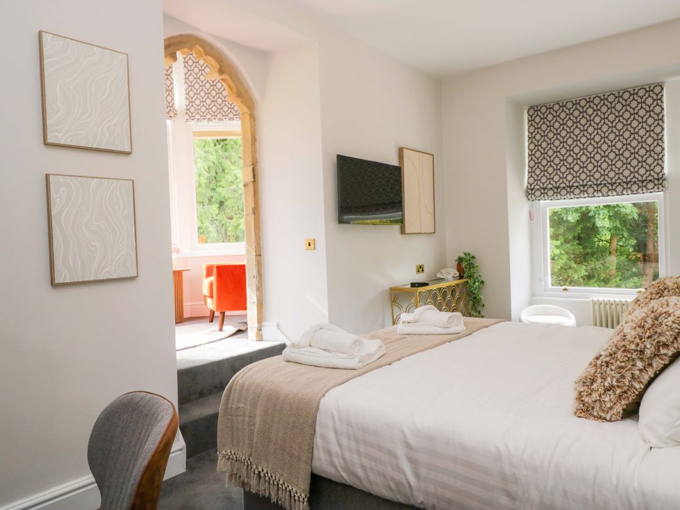 A bedroom with a bed, television, and window at Brettargh Holt Mansion Sleeping 32 near Sizergh, Cumbria