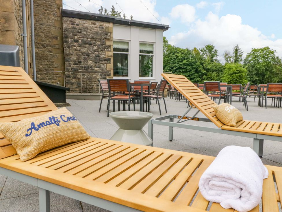 An outdoor area with lounge chairs and tables at Brettargh Holt Mansion Sleeping 32 near Sizergh, Cumbria