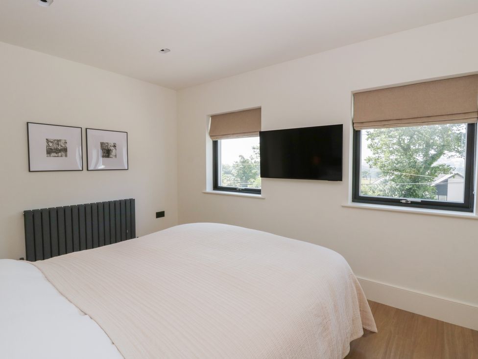 A bedroom with a bed and wall-mounted television at Brynseion Uchaf near Aberystwyth
