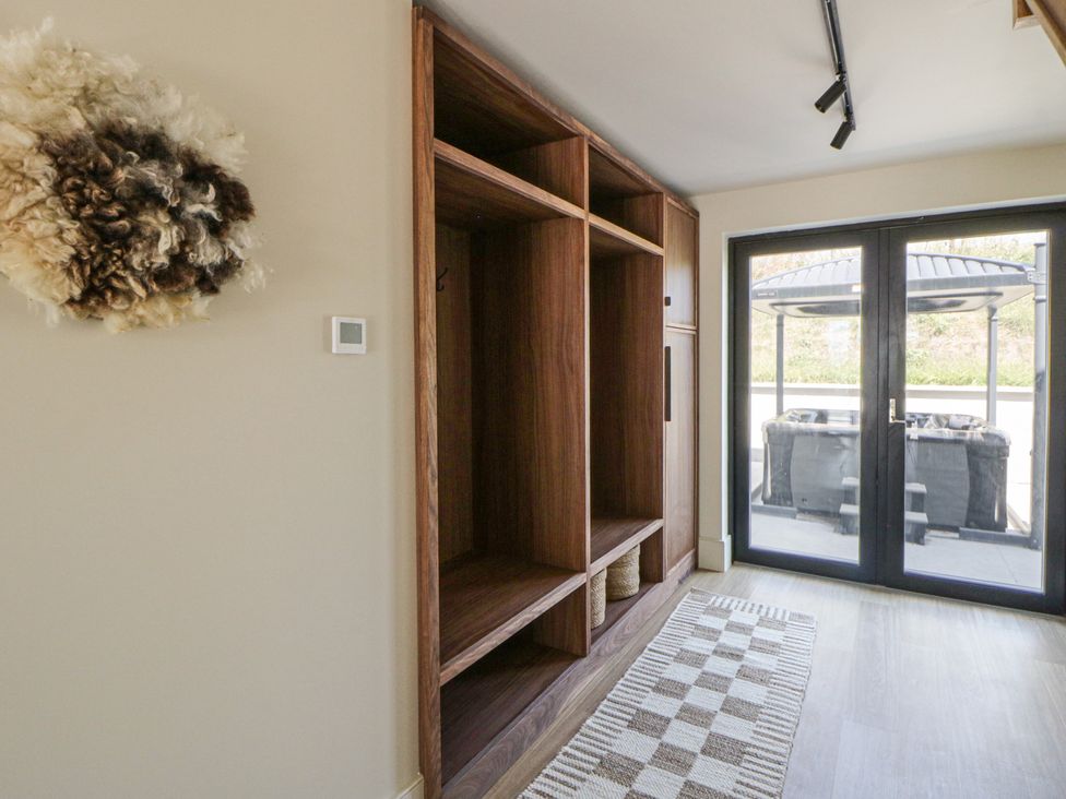 A hallway with a shelving unit and a door leading to outdoor seating at Brynseion Uchaf near Aberystwyth