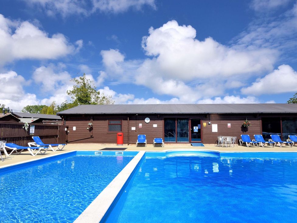 An outdoor swimming pool with sun loungers at Hazelwood 3 in Pinewood Retreat in Rousdon near Lyme Regis