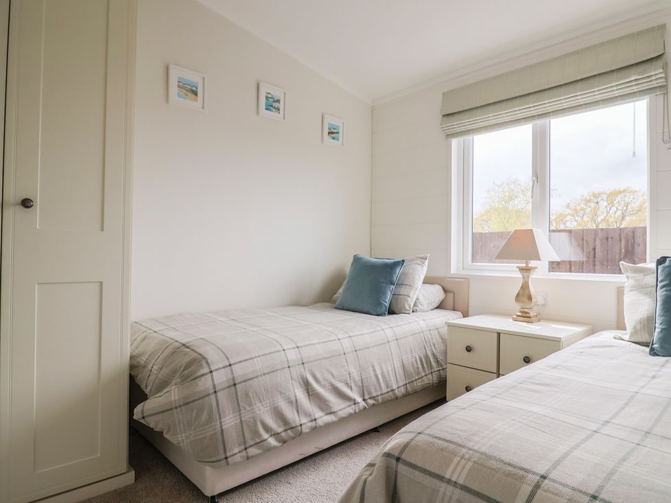 A bedroom with two beds and a bedside table at Hazelwood 3 Pinewood Retreat in Rousdon near Lyme Regis