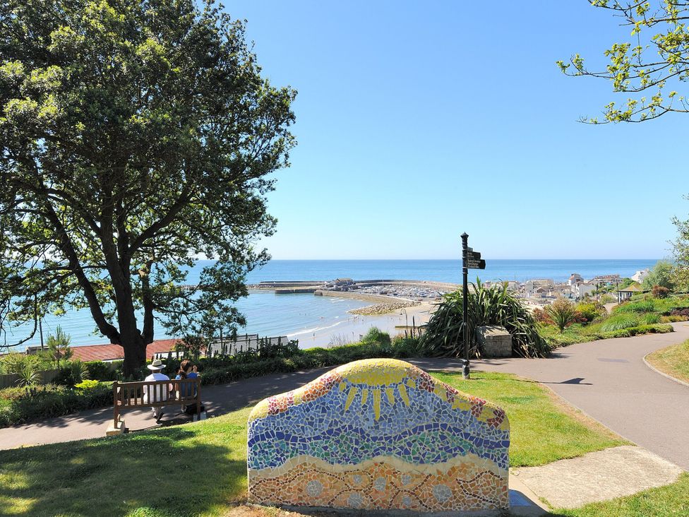 A coastal view from a park with trees and a mosaic seat at Hazelwood 3 in Pinewood Retreat in Rousdon near Lyme Regis