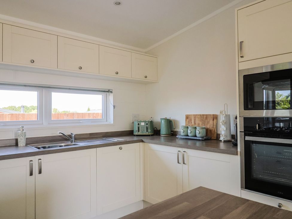 A kitchen with a sink, cabinets, and appliances at Hazelwood 3, Pinewood Retreat in Rousdon near Lyme Regis