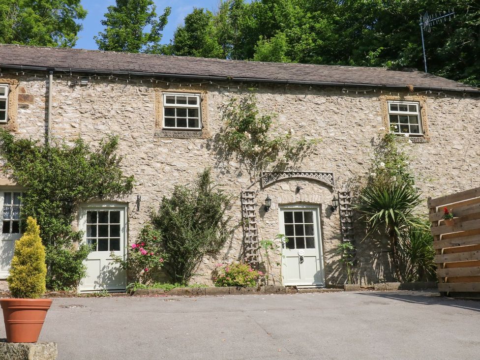 A stone exterior with windows and doors surrounded by greenery at The Barn 