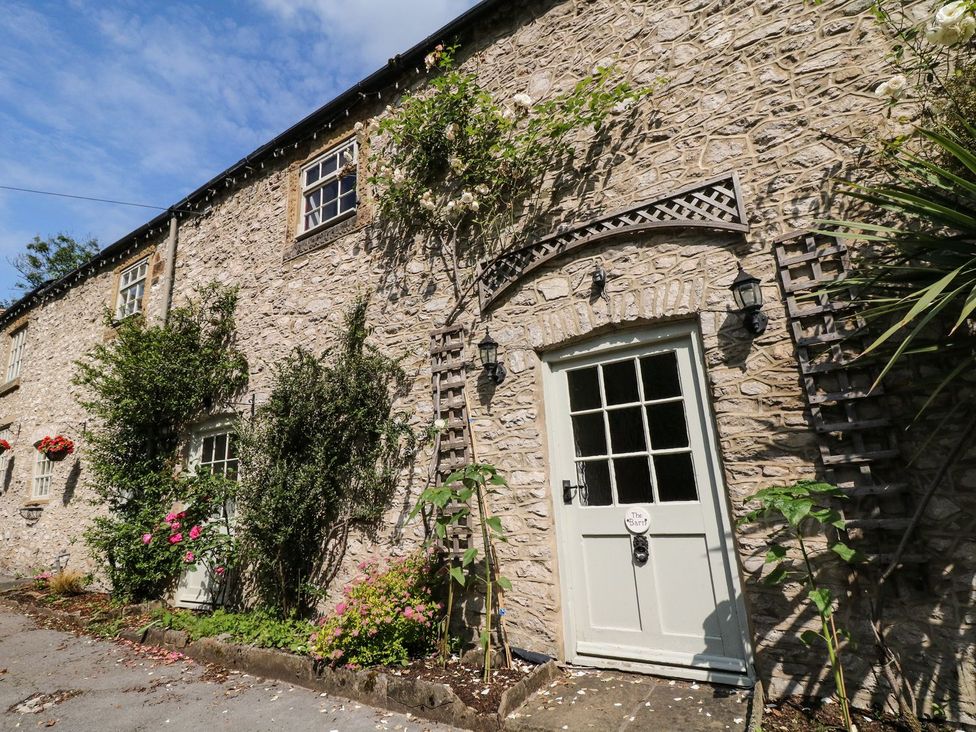 An outdoor area featuring a stone wall with a front door and plants at The Barn in 